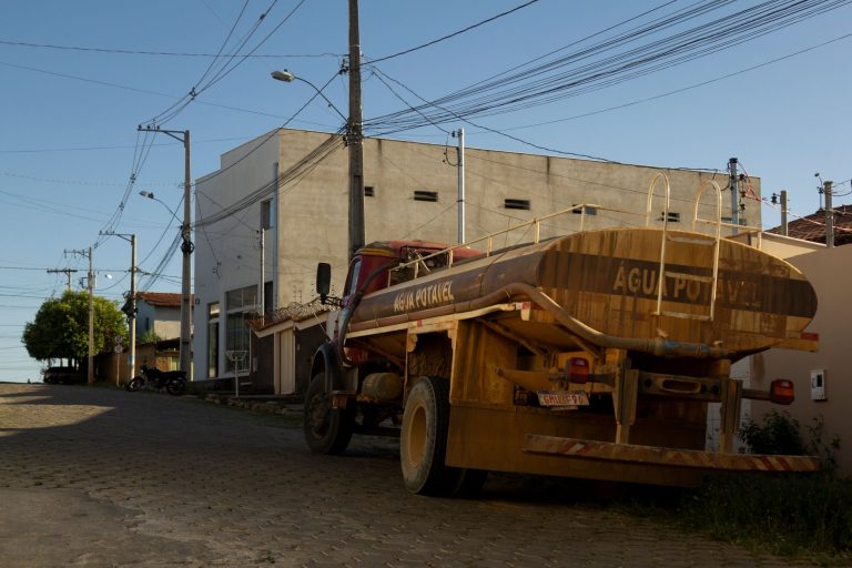 AGRESPI analisa regras para fornecimento emergencial de água por caminhões-pipa no Piauí Caminhão-pipa estacionado em uma área rural, com postes e fiação elétrica ao redor.