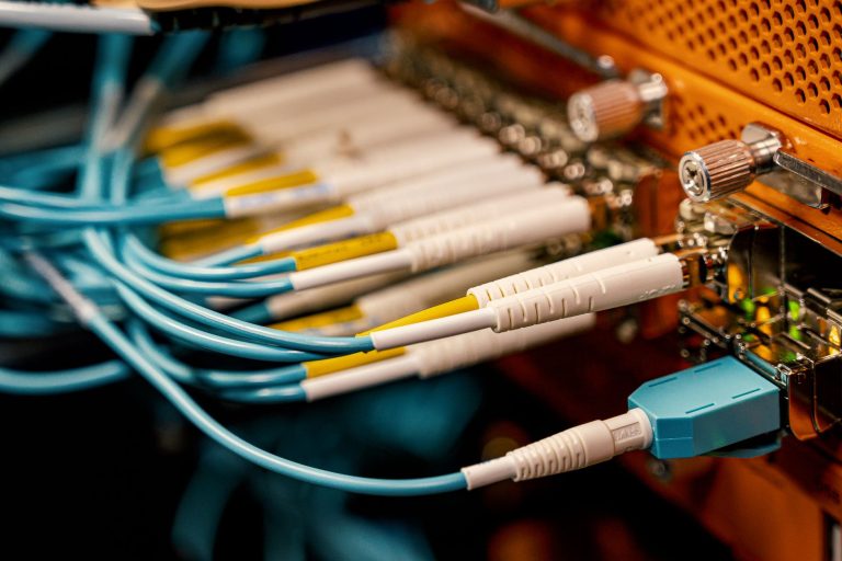 Vista superior de equipamentos de comutação óptica com diversos conectores e cabos em uma infraestrutura de telecomunicações